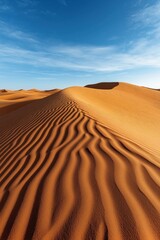 A stunning view of sand dunes in a desert landscape with rippling patterns on the sand and a clear blue sky in the background.