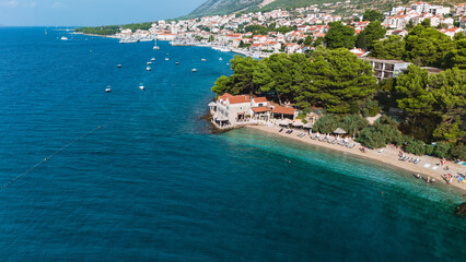 Visitors relax on the sandy shores of Brac Island, enjoying the clear blue waters and picturesque views of the coastal town. Boats drift by, enhancing the serene atmosphere of this Croatian paradise.