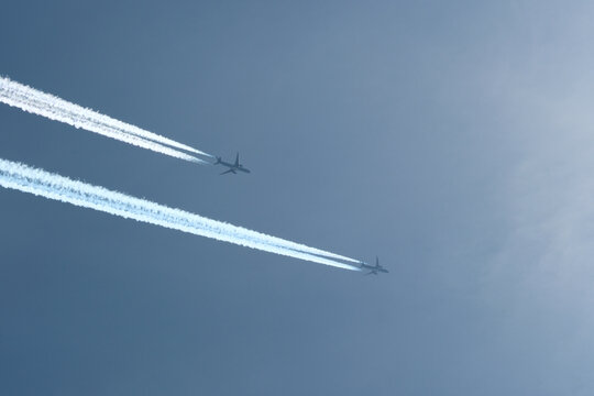 Two planes are flying towards the sun. Airplanes in the blue sky. Airplane with contrail.