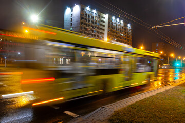 A blurred bus moves along the avenue in the evening. Shot with a long exposure.