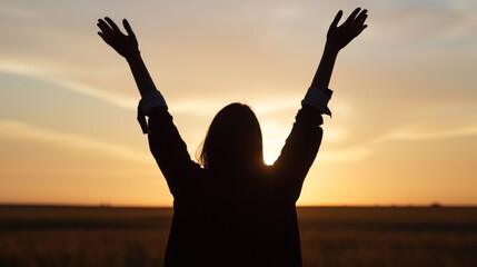 Fototapeta premium A woman stands in a vast field, silhouetted against a stunning golden sunset, her arms raised in a gesture of celebration and freedom as the day comes to a close