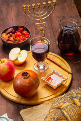 Challah, honey, pomegranate and wine on a table with a menorah in honor of Rosh Hashanah.