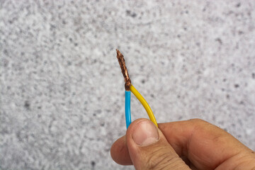 An electrician holds two bare wires twisted together in his hand.
