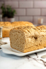 Homemade whole wheat bread with oatmeal and chia seeds and sesame seeds on kitchen table with ingredients 