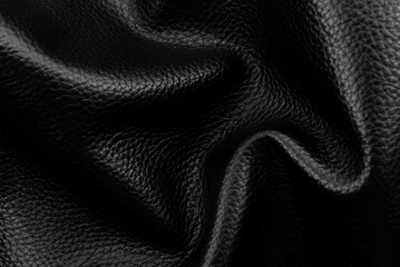 Texture of black wrinkled leather. Background of genuine leather with creases and folds