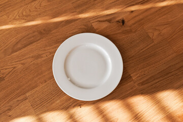 Ceramic white flat plate for food on wooden table top view