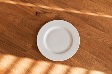 Ceramic white flat plate for food on wooden table top view