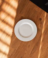 Ceramic white flat plate for food on wooden table top view