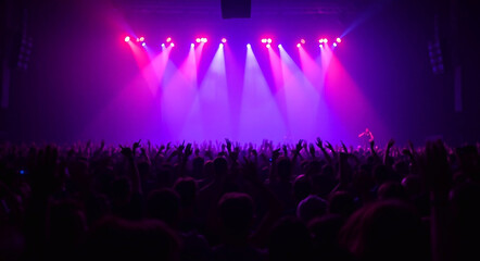 A large crowd of people at a music concert, with hands raised and vibrant lighting, creating an energetic and lively atmosphere 