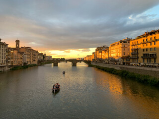 Atardecer en Florencia visto desde el Ponte Vecchio viendo el Ponte Santa Trinita con barcas surcando el r&iacute;o Arno