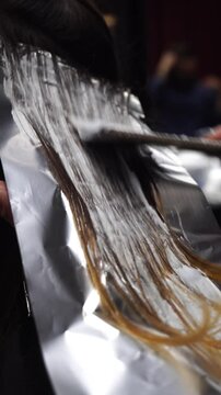 Professional stylist combs client hair after applying paint with brush. hair coloring in hairdressing salon. Close-up of hairdresser in beauty salon