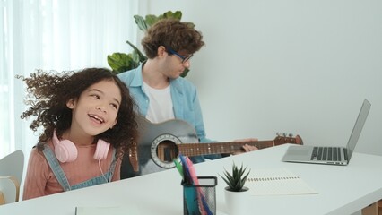 Caucasian dad play guitar and moving to music while american daughter waving and dancing to acoustic song. Happy family spend time together at home. Creative activity concept. Lifestyle. Pedagogy.