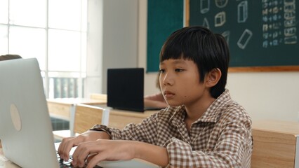 Asian boy working on his laptop while learning about coding engineering prompt at STEM technology...