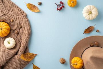 Overhead view of autumn scene featuring pumpkins, a cozy sweater, and a hat. Perfect for seasonal themes and fall decorations