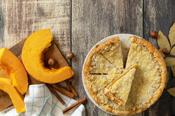 Fall traditional pumpkin pie with cinnamon on a rustic wooden background.