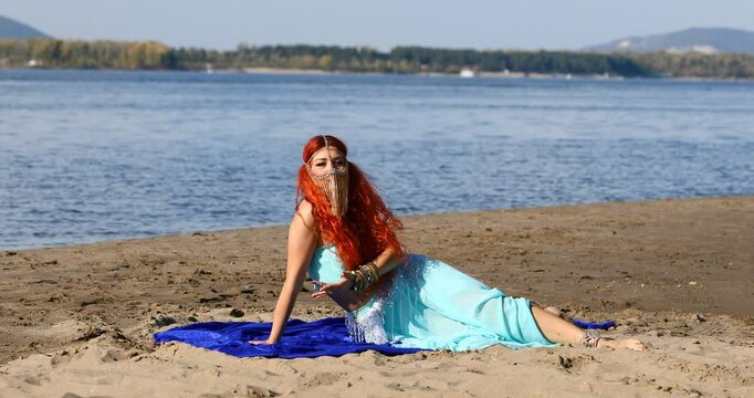 Oriental dances - a young beautiful woman dances on the beach