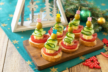 Creative appetizers christmas. Canapes Christmas tree of salami, cheese, olives, tomatoes and cucumbers with baguette on a rustic table.