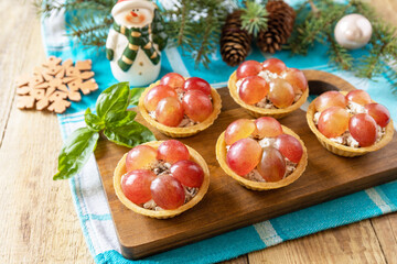 Creative appetizers christmas. Tartlets with chicken and grapes on the festive table on a rustic table.