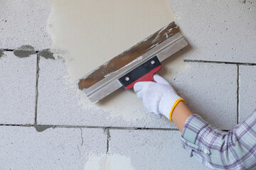 The master levels the wall with a spatula.