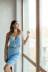 Beautiful young adult model in blue dress in white room