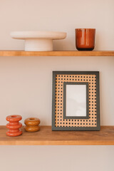 Close-up of assorted ornaments, vase and  blank picture frame on shelves.
