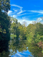 Autumn landscape with blue sky and trees reflected in the water