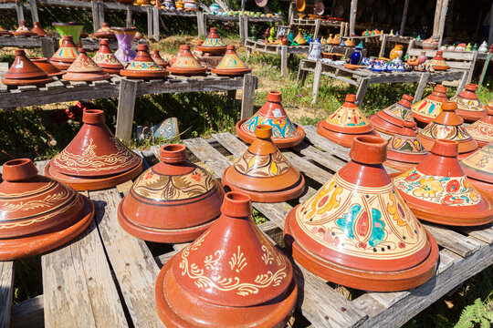 tajInes de cer&aacute;mica adornados expuestos  para su venta en una tienda de carretera en Marruecos