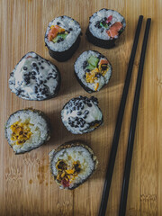 Sushi rolls with salmon, tuna and caviar on wooden background