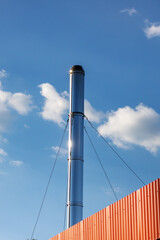 A very tall chimney standing out against a blue sky filled with clouds