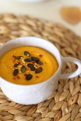 Pumpkin and potato creamy soup, bowl of grapes, jars of nuts and autumn leaves on the table. Selective focus.