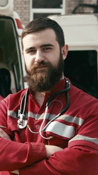 Portrait of a male ambulance doctor standing proudly in front of the camera in a medical orange uniform. Successful emergency medical technician or doctor at work.