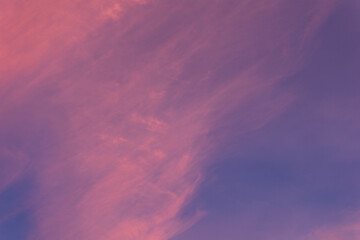Wispy pink and purple clouds are blending together, creating a dreamy and abstract pattern against the vast expanse of the evening sky