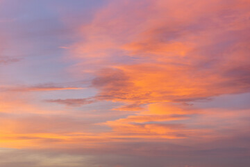 Vivid orange clouds are swirling in the vast expanse of the twilight sky, creating a captivating display of nature's artistry