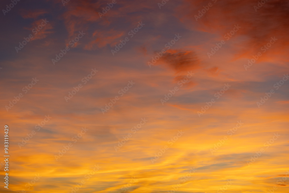 Aufkleber wispy clouds are glowing in the evening sky, creating a mesmerizing display of orange and yellow hue