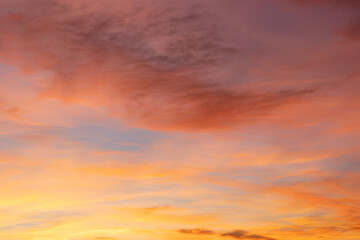 Captivating sunset with fiery orange, warm pink, and soft purple hues, as wispy clouds dance across the horizon
