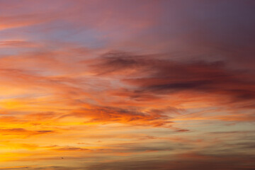 The sky is filled with vibrant orange and purple hues as the sun sets below the horizon, casting long shadows and creating a warm glow