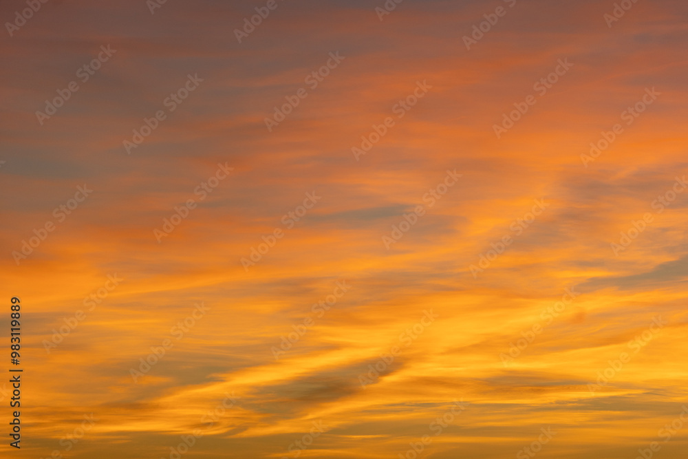 Poster glowing wispy clouds at sunset transition to evening, casting colorful rays in a serene sky. perfect