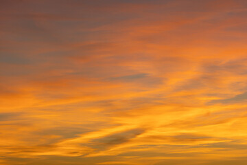 Glowing wispy clouds at sunset transition to evening, casting colorful rays in a serene sky. Perfect for vibrant and calming views