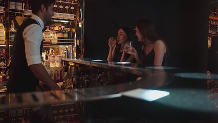 Portrait of VIP guest in beautiful woman making a toast in cheers at luxurious nightclub at vibrant nightlife party. Sitting at counter bar talking with barman atmosphere party lifestyle. Vinosity.