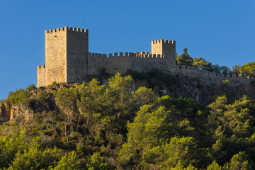 CastView of Sesimbra castle from the valley with a blue sky. The valley is covered with trees and...