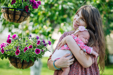 Fototapeta premium Mother cradles her slumbering baby girl amid a lush garden of vibrant purple and pink blooms