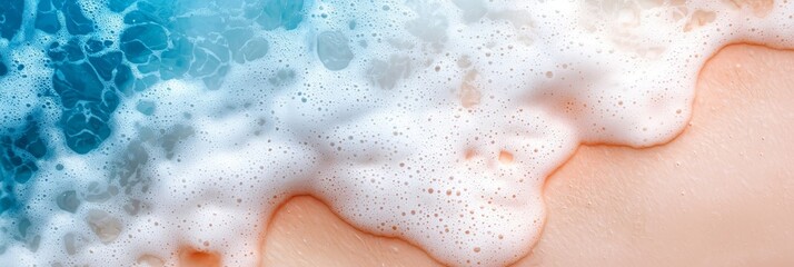 Fototapeta premium A tight shot of a frothy wave on a sandy shore against a backdrop of a blue-white ocean