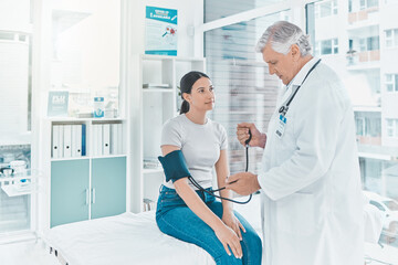 Doctor, woman patient and check blood pressure in hospital, assessment and healthcare. Mature man,...