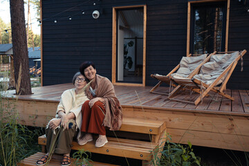 Asian senior adult women sisters sitting outdoors on suburb house terrace