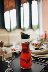 A jug of juice and an empty glass on the table.