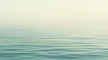 Obraz premium Serene calm of the ocean surface at dawn with gentle ripples under soft light and a hint of fog in the air