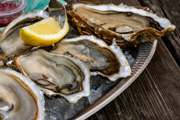 Plate with fresh live oysters with citron, bread, butter and white wine served on ice at restaurant...