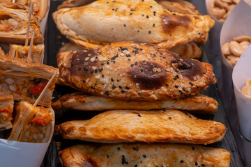 Traditional Spanish and Latin American pies empanadas with different fillings, at farmer's market in bakery with tuna fish, sweet onion, goat cheese, bacon
