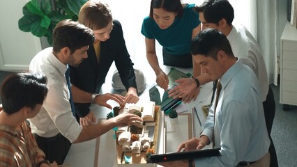 Top down view of manager pointing at house model and explain building design. Aerial view of architect engineer brainstorming about interior construction while tablet display house plan. Alimentation.