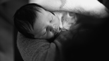 Newborn baby sleeping peacefully in mother’s arms. The intimate scene emphasizes the calm and...